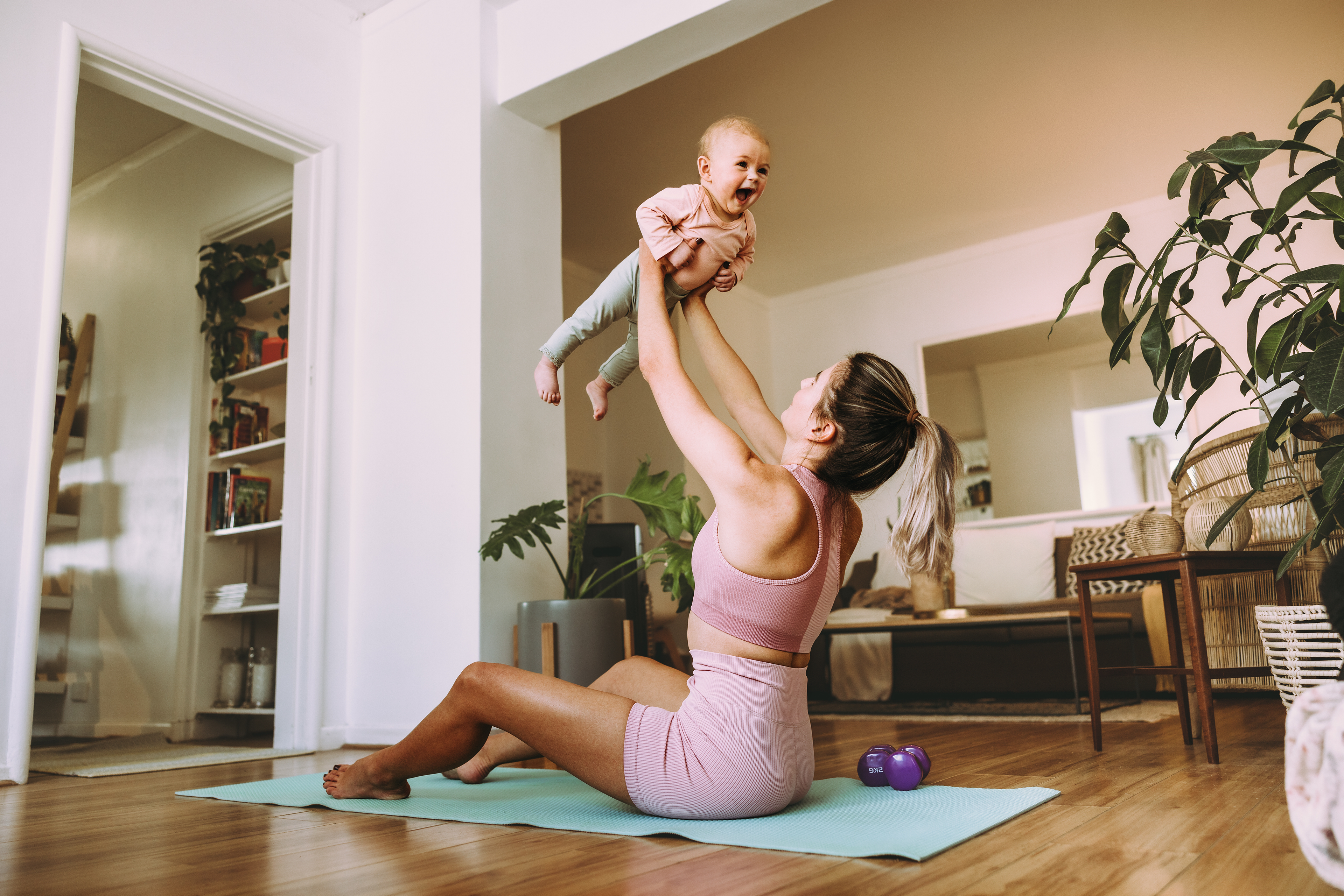 Woman exercising with a baby on a yoga mat in a home setting